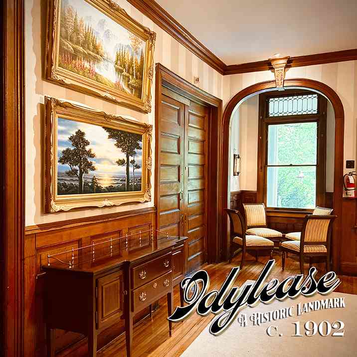 Historic Idylease lobby with woodwork, arched window, and framed paintings