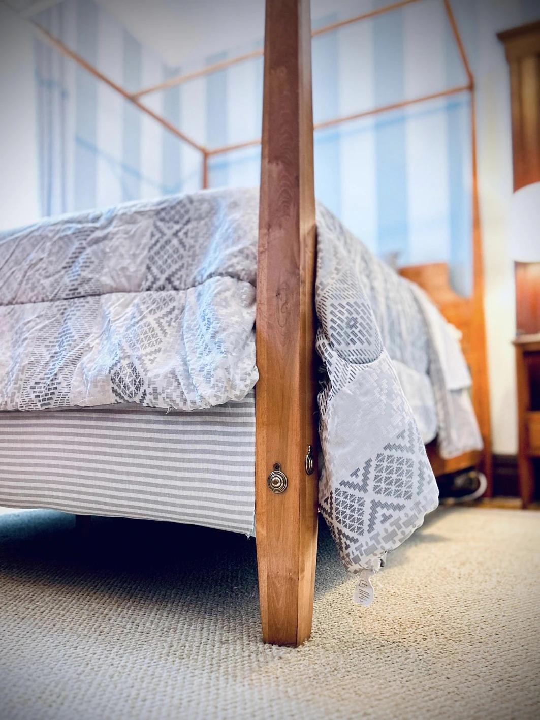 Four-poster bed detail at Idylease showing wood bedpost, patterned bedding, and textile finishes