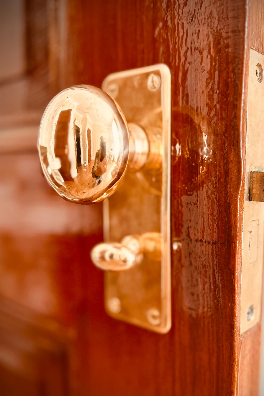 Original brass doorknob and lock hardware on a wood door at Idylease